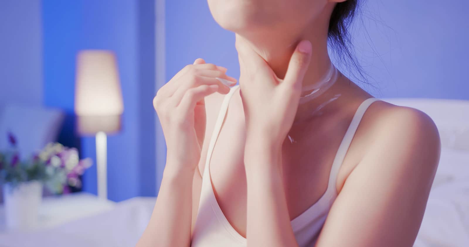 donna applica crema al collo prima di andare a dormire